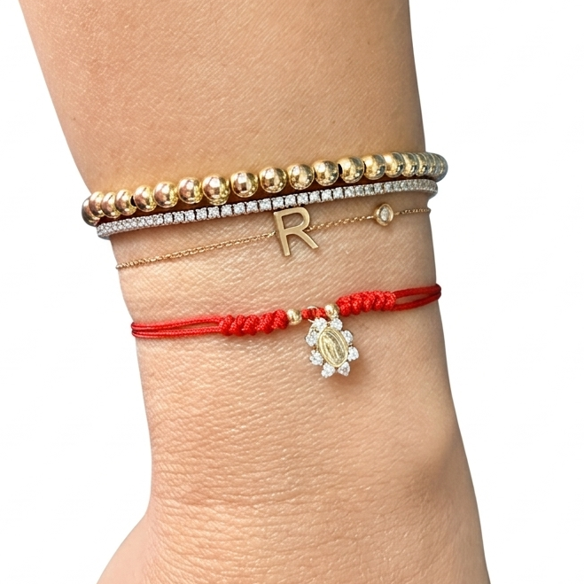 14K solid yellow gold CZ miraculous medal red string adjustable bracelet styled on wrist with fine gold bracelet stack