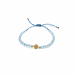Blue macramé bracelet with faceted blue topaz gemstones and a gold miraculous medal charm, adjustable cord with gold bead accents.