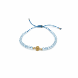Blue macramé bracelet with faceted blue topaz gemstones and a gold miraculous medal charm, adjustable cord with gold bead accents.